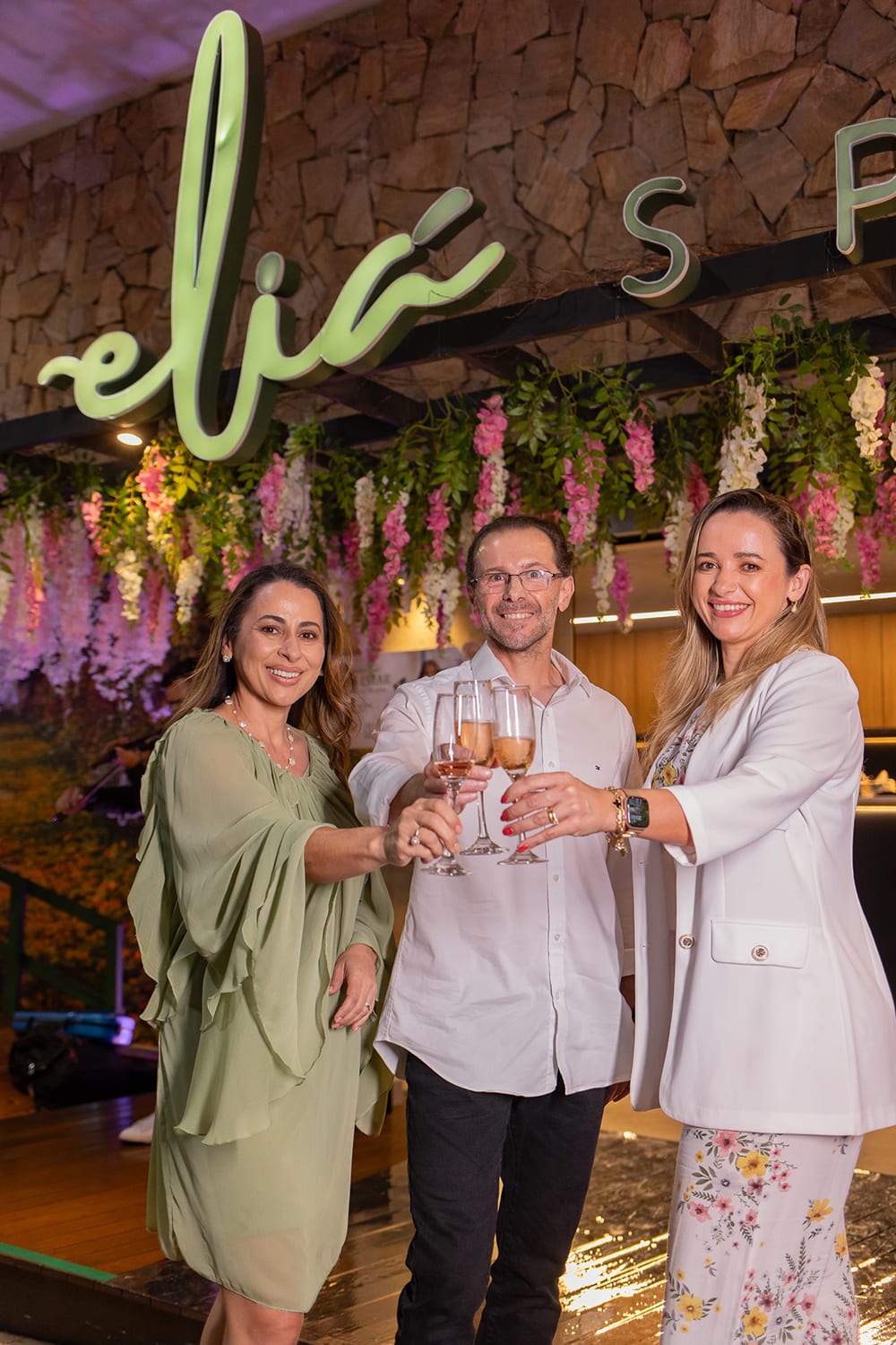 Fundadores da Eliá Spa brindando sob o letreiro da marca